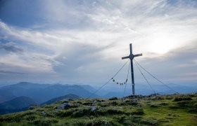 Lackenhof, Ötscher, Großer Ötscher, Wandern, Bergsommer, Ötschergipfel, Gipfelkreuz, © Ötscherlifte, Ludwig Fahrnberger Ein majestätisches Gipfelkreuz thront über den sanften Hügeln, umgeben von einer atemberaubenden Berglandschaft. Die Wolken ziehen sanft über den Himmel und verleihen der Szenerie eine friedliche Atmosphäre, während die frische Bergluft zum Wandern einlädt.