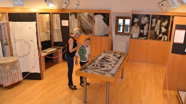 Handarbeitsmuseum, © Martina Heigl Zwei Personen betrachten Exponate in einem Handarbeitsmuseum.