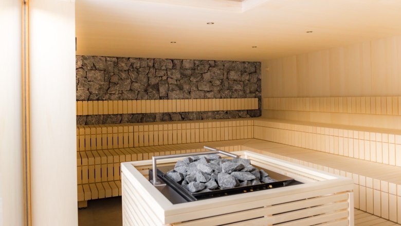 20251104_ybbstaler solebad_sauna_(C) Rene Jagersberger, © Rene Jagersberger Interior view of a modern sauna with wooden benches and a stove with stones in the middle.
