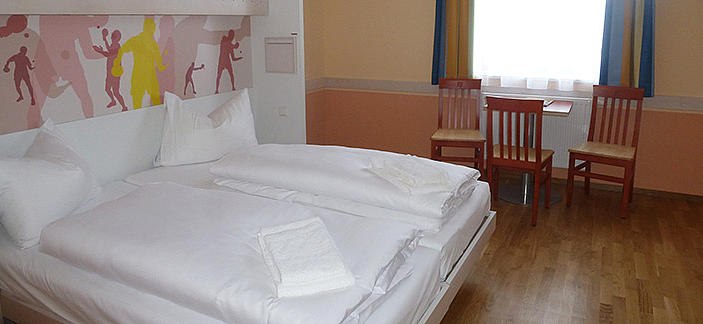 JUFA Hochkar, © JUFA Hochkar Sport Resort Hotel room with double bed, two chairs and a table in front of a window.