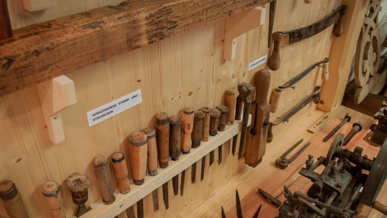 Verschiedene Stemm- und Stecheisen, © Rene Jagersberger Eine Sammlung von Holzwerkzeugen, darunter Stemm- und Stecheisen, an einer Holzwand ausgestellt.