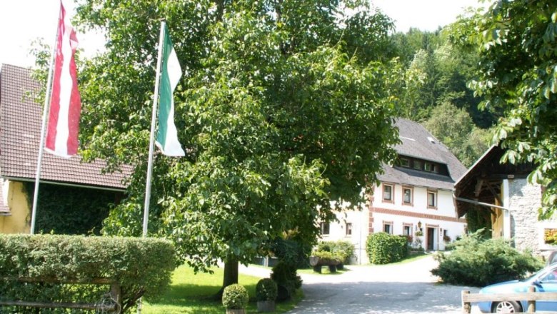 Moarhof vacation farm, © Feriengut Moarhof A traditional farmhouse with a garden and flags in the foreground.
