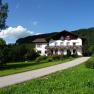 Bauernhof Sinsamreith, © Bauernhof Sinsamreith Ein Bauernhof mit Blumen geschmücktem Haus in einer grünen Landschaft unter blauem Himmel.