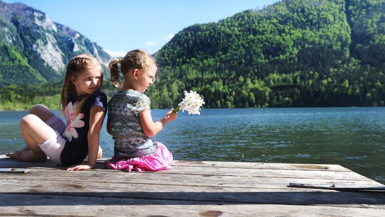 Die Natur am Lunzer See genießen, © weinfranz.at Zwei Kinder sitzen auf einem Steg am Lunzer See mit Bergen im Hintergrund.