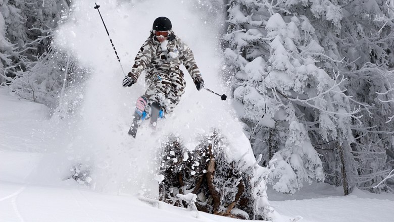 Hochkar ski area, © WeinFranz Skier jumping through powder snow in the forest.