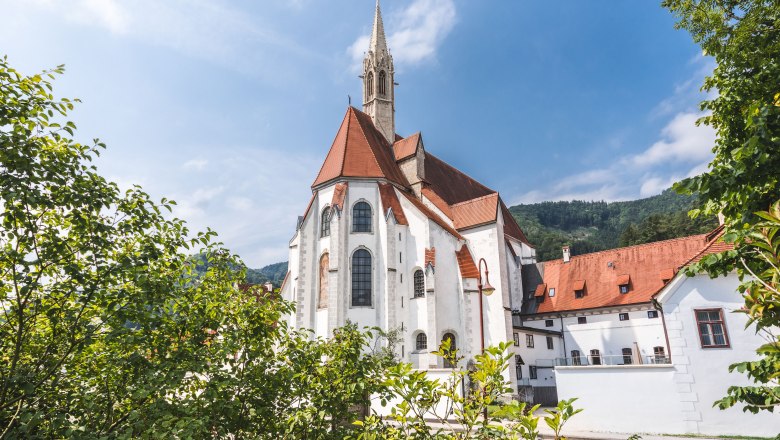 Hotel Kartause Gaming, © Ricarda Schwarzel Historisches Gebäude mit rotem Dach und Turm, umgeben von Bäumen.