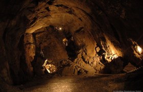 Hochkar cave, © Hochkar Bergbahnen GmbH Interior view of an illuminated cave with stony walls and a narrow path.