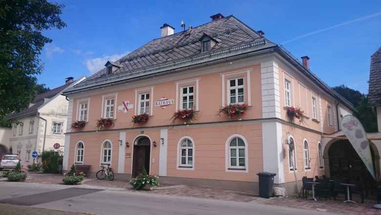 Marktgemeindeamt Göstling, © Tourismusverein Göstlinger Alpen Ein zweistöckiges, rosa Gebäude mit weißen Fensterrahmen und Blumenkästen, beschriftet mit 'Rathaus'.
