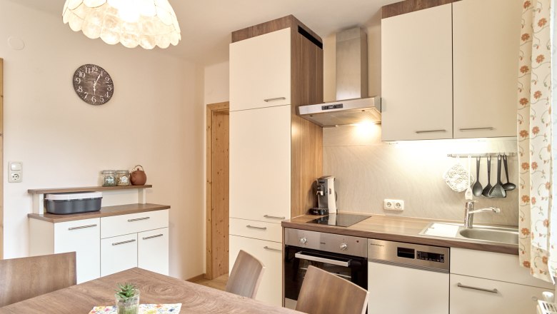 Sonnige Ferienwohnung 1 - Küche, © Auftragsfoto.at Moderne Küche mit Holz- und Weißtönen, Esstisch, Hängelampe und Küchengeräten.