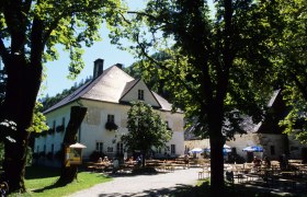 Jausenstation Herrenhaus, © Jausenstation Herrenhaus Ein Herrenhaus mit Biergarten im Grünen, umgeben von Bäumen.