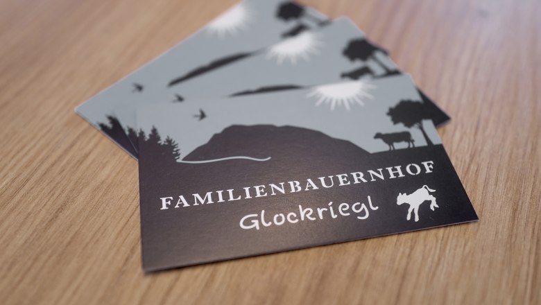 Visitenkarten Familienbauernhof Glockriegl, © Auftragsfoto.at Postkarten mit dem Logo des Familienbauernhofs Glockriegl auf einem Holztisch.