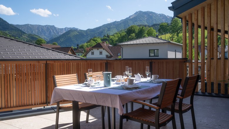 (c)liegrafie (7), © liegrafie A laid table on a terrace with a view of mountains and houses.
