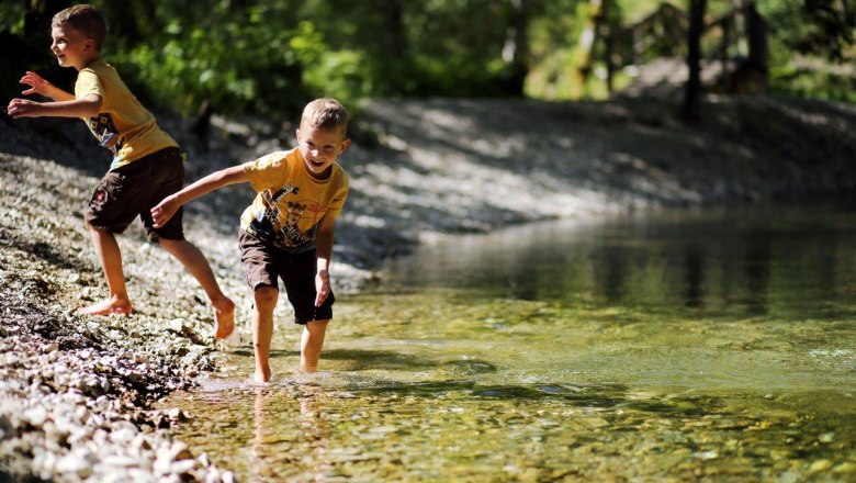 Mendlingtal experience, © weinfranz.at Two children play in nature on the banks of clear water.
