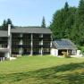 BS Ötscher Hotel im Sommer, © Familie Butt Hotelgebäude mit Solarpanelen und grüner Wiese im Vordergrund, umgeben von Wald.