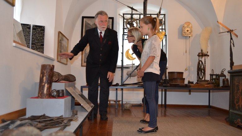 Hammer Herren Museum, © Heigl Martina An elderly man shows two women historical objects in a museum.