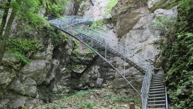 Adventure trail up to the Ötscher stalactite cave, © Melanie Karas Metal stairs in a rocky gorge with green vegetation.