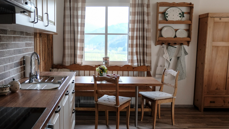 Amon Küche, © Raphaela Bachler A cozy kitchen with wooden furniture and a view of the mountains through the window.