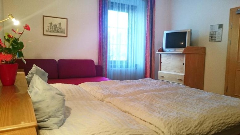 Doppelzimmer, © Hotel Zum Goldenen Hirschen Ein gemütliches Doppelzimmer mit Bett, Sofa, Fernseher und Fenster.