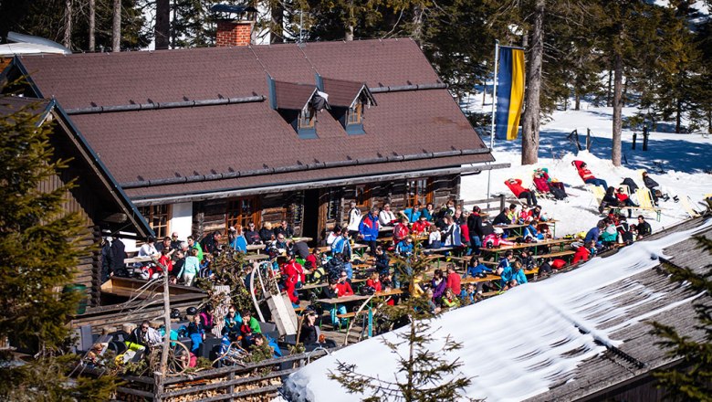Karhütte Hochkar, © Karhütte Menschen sitzen vor einer Berghütte im Schnee, umgeben von Bäumen.