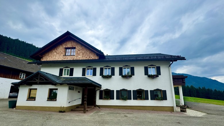 image00019_1, © Familie Buber A traditional two-story farmhouse with white walls and black shutters.