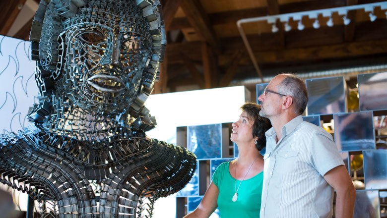 FeRRum - welt des eisens, © Dominik Stixenberger Zwei Personen betrachten eine große Metallskulptur in einer Ausstellung.