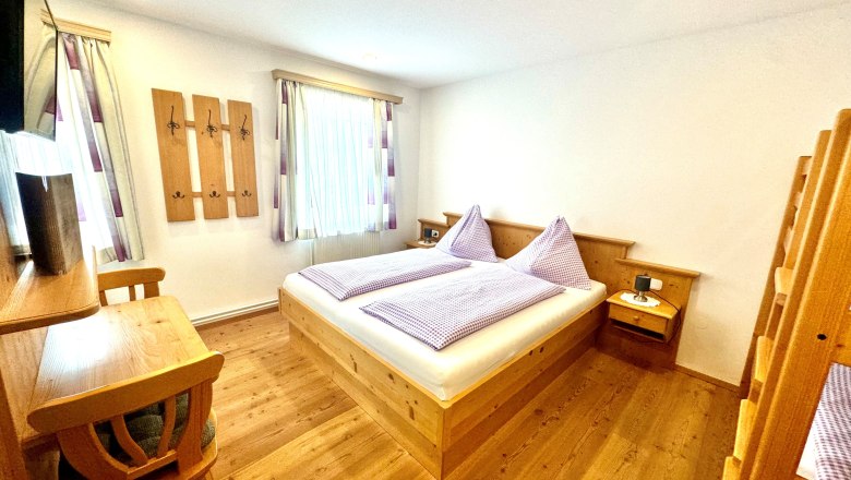 image00018, © Familie Buber A cozy bedroom with wooden furniture, a double bed, and a bunk bed.