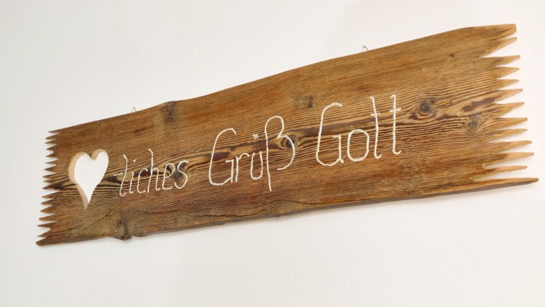 4-glockriegl_0214_fullsize, © grasberger Wooden sign with the inscription 'Herzliches Grüß Gott' and a heart symbol.