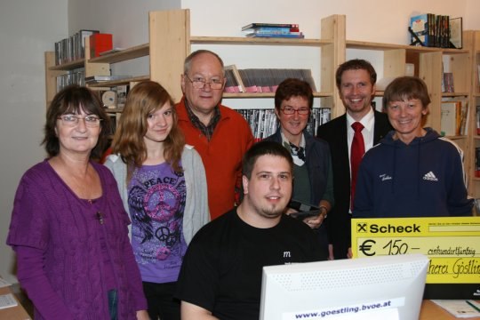 Group of people in a library with a check for 150 euros.