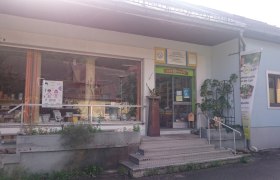 Eingang eines Gesch&auml;fts mit Schaufenster und Pflanzen.