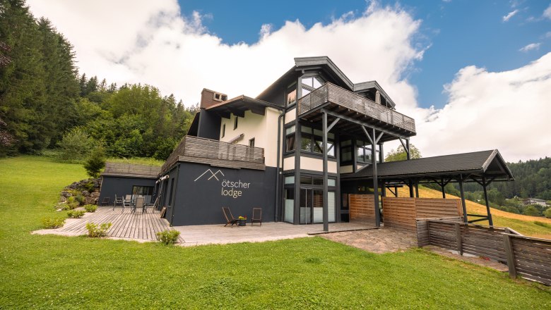 &Ouml;tscher Lodge in a green, wooded setting with a blue sky.