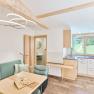 Modern apartment with wooden elements, kitchenette and dining table. Windows with a view of the green landscape.