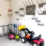 Innenansicht einer Garage mit Kinderfahrzeugen und Skischuhhaltern an der Wand.