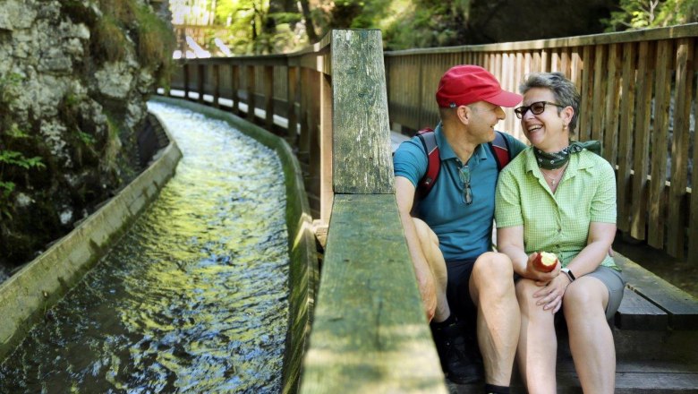 Ein Pärchen macht eine Pause auf den Stufen des Wanderstegs, direkt neben dem Triftkanal.