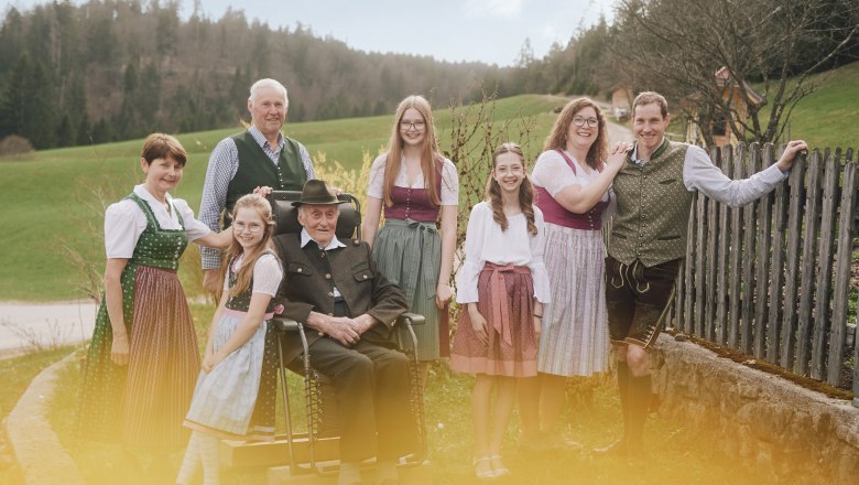 Eine Familie in traditioneller Tracht posiert im Freien vor einer l&auml;ndlichen Kulisse.