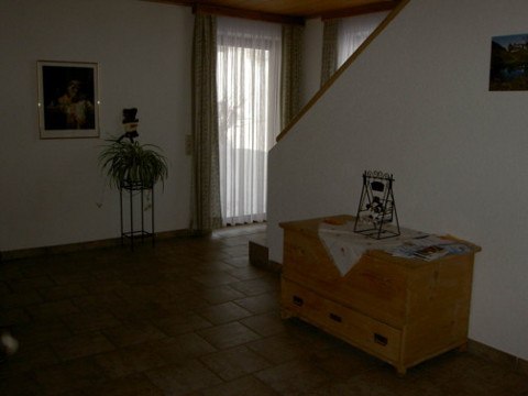 Interior view of a living area with wooden box, plant and stairs.
