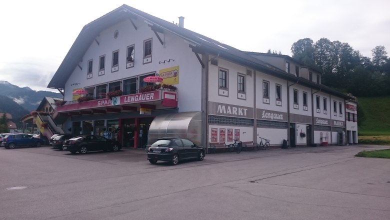 Geb&auml;ude mit Spar-Lengauer-Markt und Post-Partner-Schild, Autos und Fahrr&auml;der davor.