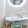 Modernes Badezimmer mit rundem Spiegel, Waschbecken und Handt&uuml;chern.