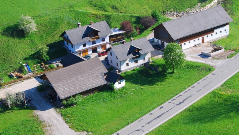 Aerial view of a farm with several buildings and green meadows.