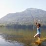 Eine Frau macht Yoga in einem See mit einem Berg im Hintergrund.