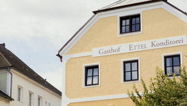 Gelbes Gebäude mit der Aufschrift 'Gasthof Ettel Konditorei'.