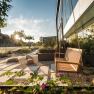 Garden with rocking bench, gravel path and plants, in the background a castle at sunset.