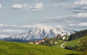 Blick auf St. Leonhard am Walde mit schneebedecktem Berg im Hintergrund.