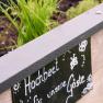 Ein Hochbeet mit Kr&auml;utern und einem Schild mit der Aufschrift 'Hochbeet f&uuml;r unsere G&auml;ste'.