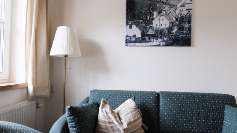 Wohnzimmer mit Sofa, Stehlampe und Bild an der Wand.