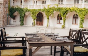 A table set in a historic courtyard with vines on the walls.