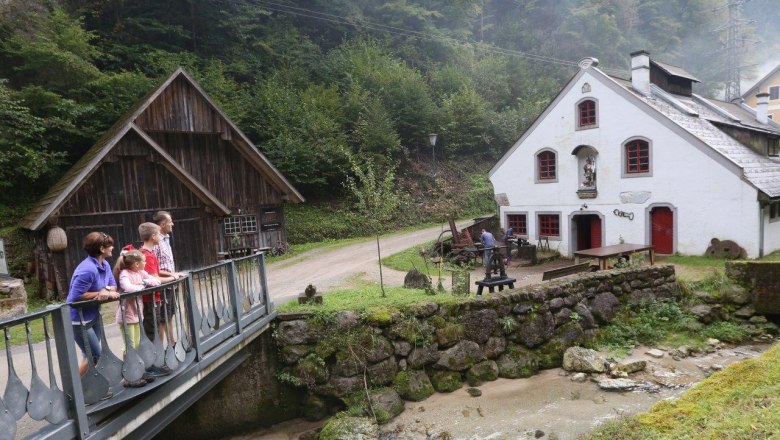 A family stands on a bridge in front of a historic building in a rural setting.