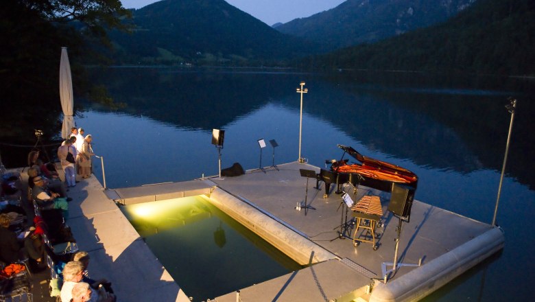 Seebühne Lunz am See bei Abenddämmerung mit Klavier und Zuschauern.