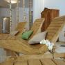 Innenansicht eines Wellnessbereichs mit Holzliegen, Kissen und Birkenstämmen.