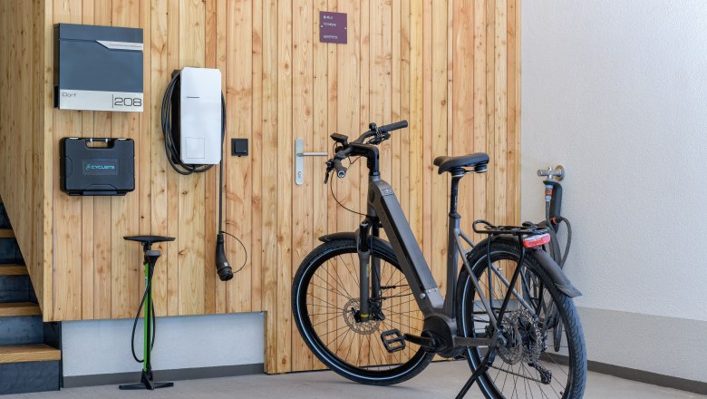 Ein modernes E-Bike steht in einer Garage neben einer Ladestation an einer Holzwand.