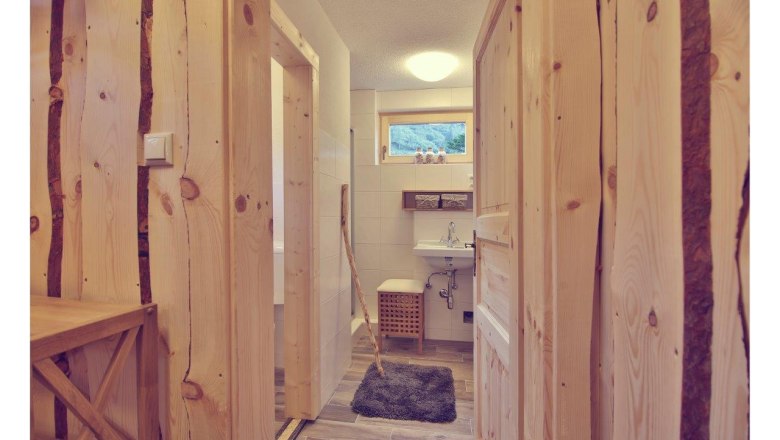 Interior view of a bathroom in a chalet with wooden walls and doors, washbasin and small window.